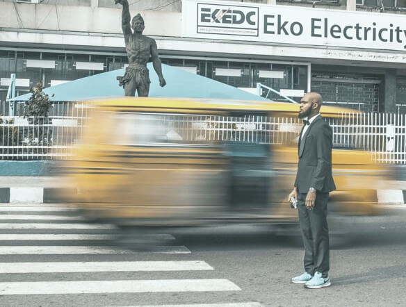 a suit-wearing man stands by a road